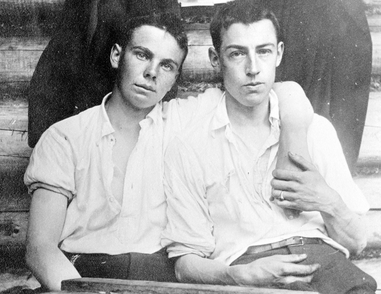 Cub sits with his arm around Len’s shoulders while Len holds his forearm; both wear open-neck shirts.